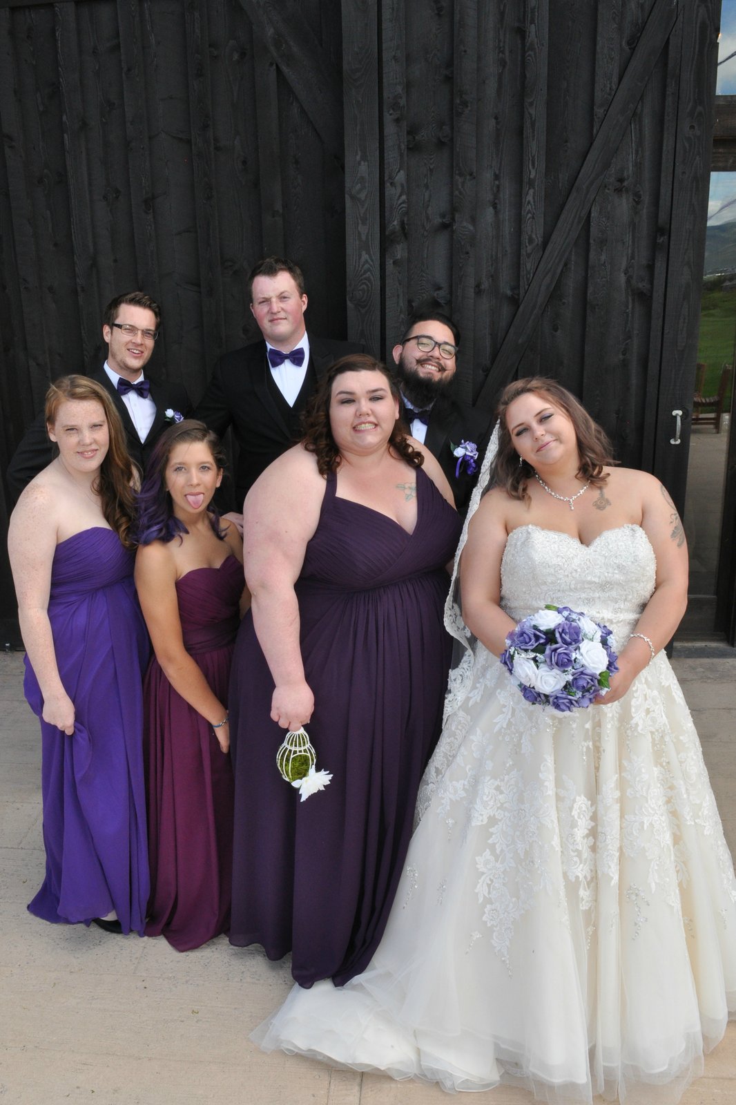 Bride and wedding party by dark barn doors