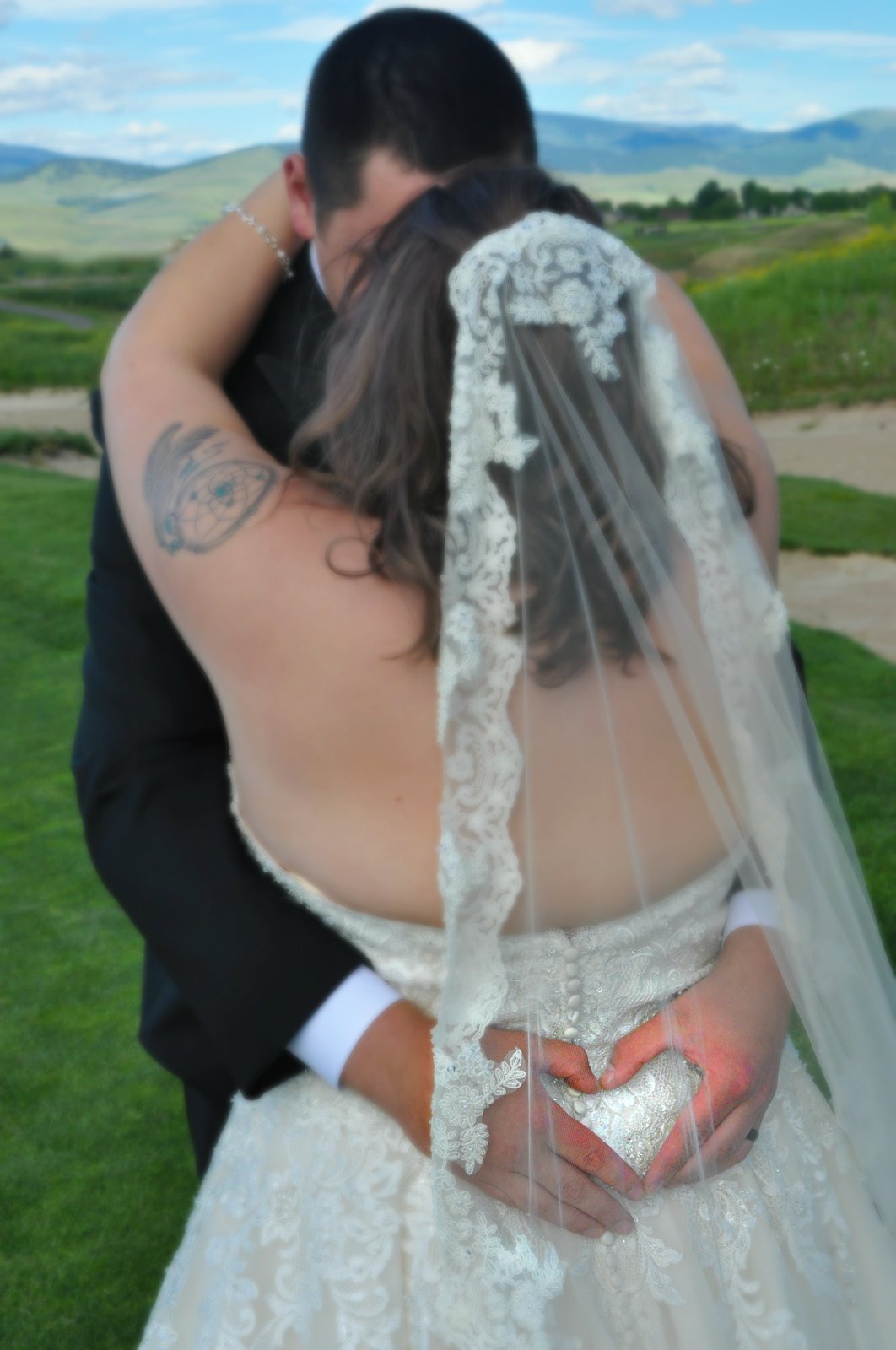 Couple embrace with mountain view and heart-shaped hands